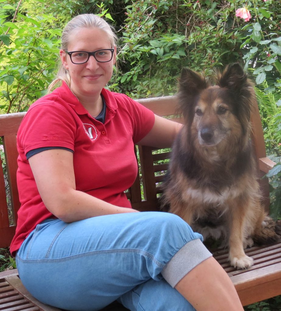 Tierarzthelferin Nina Thiem auf einer Bank und neben ihr ein Hund